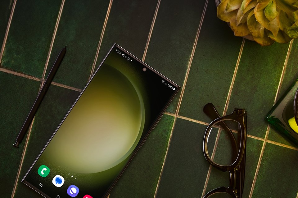 A Samsung Galaxy S23 Ultra smartphone next to a pair of glasses on a table.